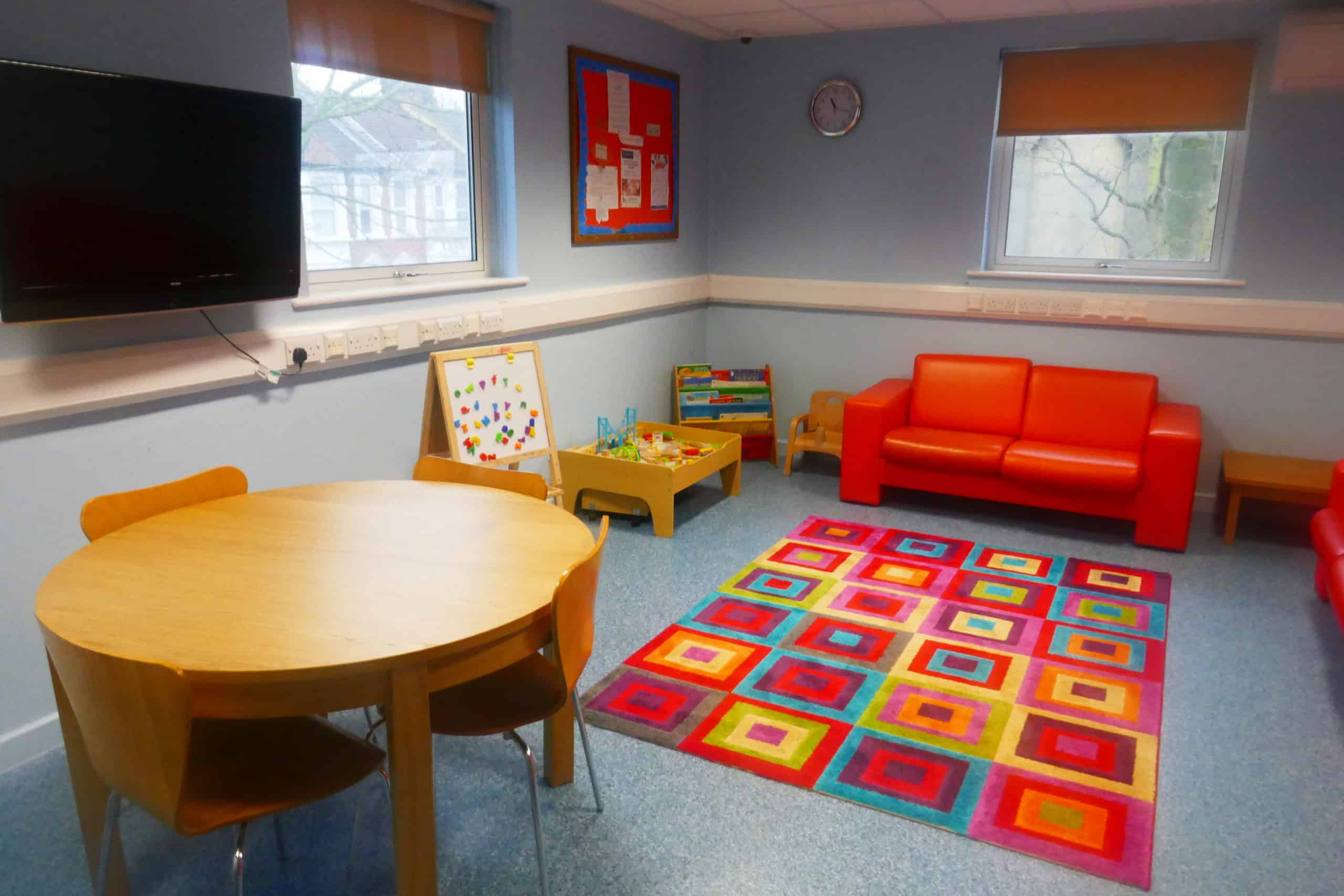 Contact room number 6, with a table, play mat, sofa and television